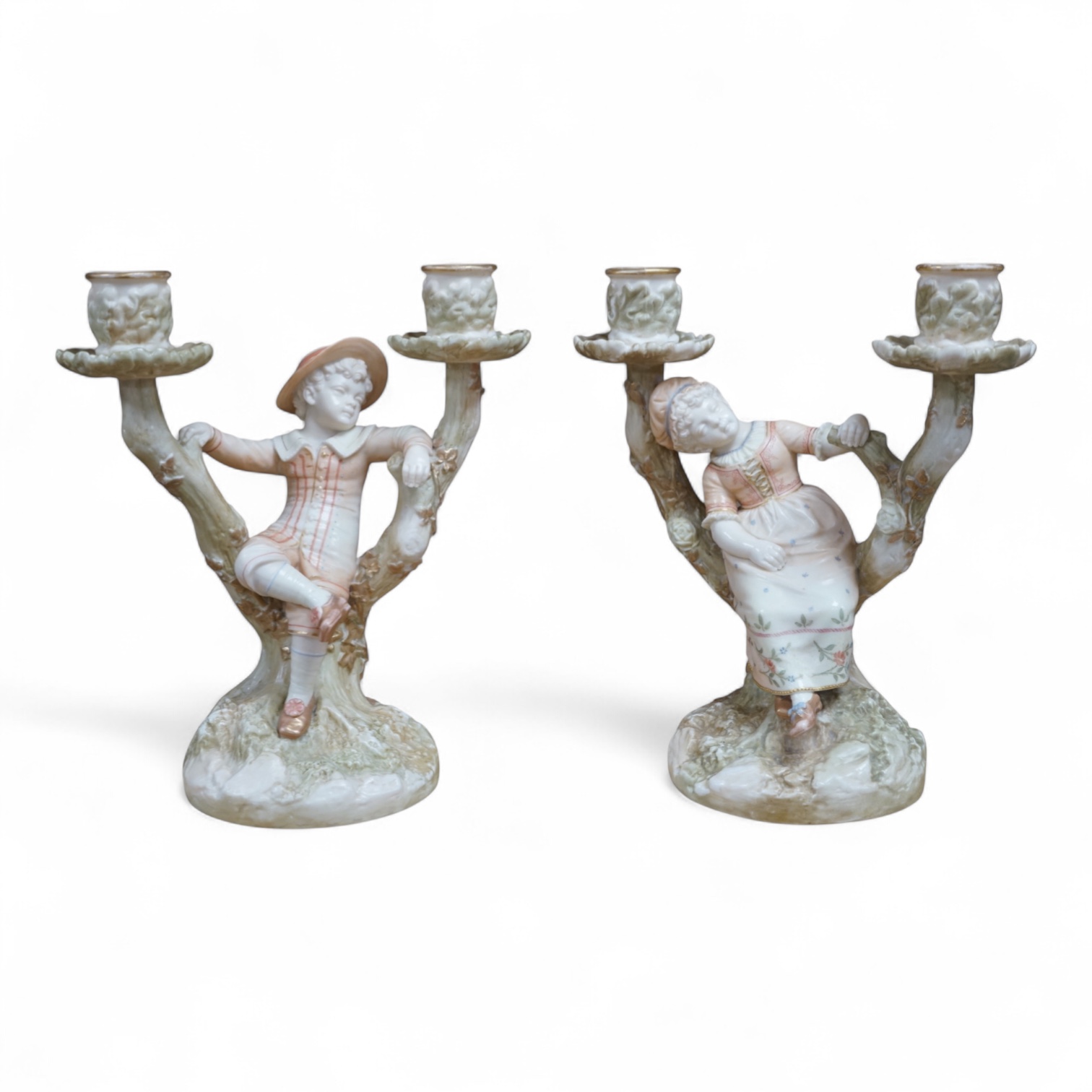 A pair of late 19th century Royal Worcester Kate Greenaway style figural two branch candelabra, modelled by James Hadley 22.5cm high